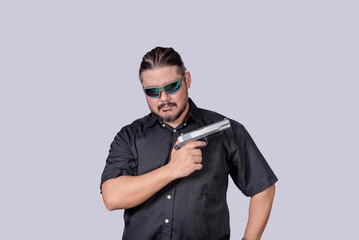 Obraz premium A ganster or henchman wearing shades showing off his handgun, in an act of intimidation.