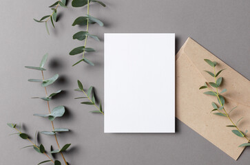 Blank wedding botanical invitation card mockup with fresh eucalyptus and envelope on grey