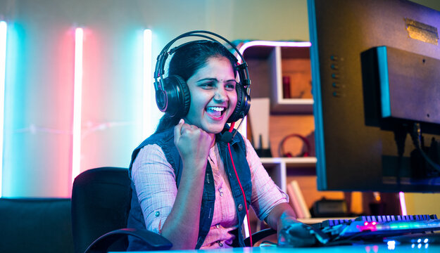 happy gamer celebrating win or victory while playing online video game tournament on computer at home - concept of success, championship and live streaming.