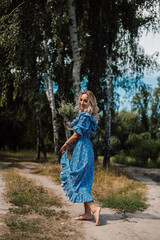 A young attractive woman with flowers in her hands walks through the forest