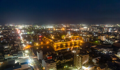 Obraz premium Major road runs by historic Japanese castle surrounded by modern city at night