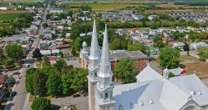 High angle drone shot of the St-Jacques de Montcalm church rotating around the bells and revealing the village around it