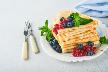 Pancakes. Stack of crepes or thin pancakes with berries, blueberries, red currants, raspberries and honey for breakfast. Homemade breakfast. Copy space. Selective focus.