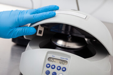 Closeup of a scientist closing an small table centrifuge filled with tubes. Spin column-based nucleic acid purification technique. Diagnosis of human papillomavirus virus infection.