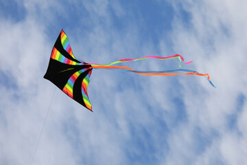 kite with black color and many colors of rainbow flying high attached to a string
