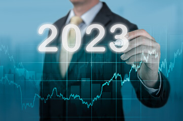 Businessman in suit forecast analysis plan profit chart. economic forecasts for 2023. businessman writes 2023 on virtual screen. economic recovery after fall due to covid-19 coronavirus pandemic