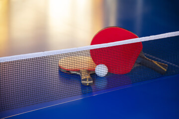 blue tennis table with two rackets, white net ball, leisure activities