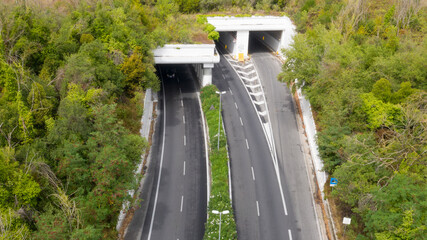 Aerial view on two tunnels that enter the mountain. The streets are empty.