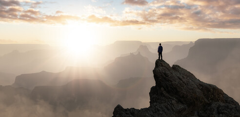 Epic Adventure Composite of Man Hiker on top of a rocky mountain. Dramatic Sunset Sky. 3d Rendering peak. Background landscape from North America. Freedom Concept.
