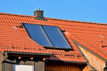 Solarthermieanlage zur Warmwassererzeugung auf rotem Hausdach