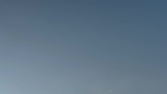 Timelapse of white clouds moving over a beautiful blue sky, on a sunny spring evening. During the timelapse, it&rsquo;s getting darker. A plane crosses the sky in the end. Stock video footage 4K