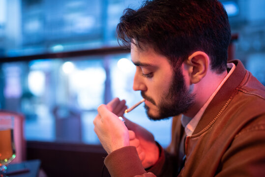 man smoking cigar in bar terrace, snuff rolling