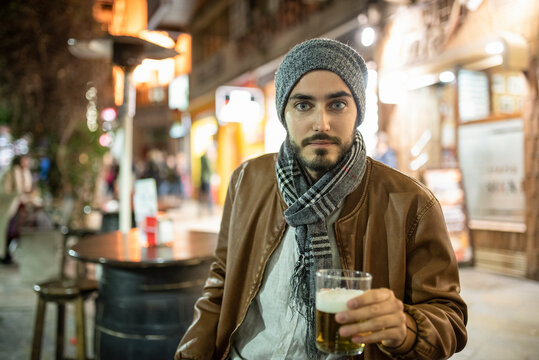 Young man drinking beer in bar terrace, winter image.