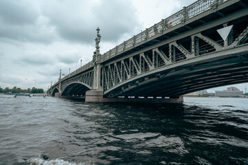 Fototapeta na wymiar Bridge. A low metal bridge across the river in cloudy weather in gloomy dark colors. St. Petersburg