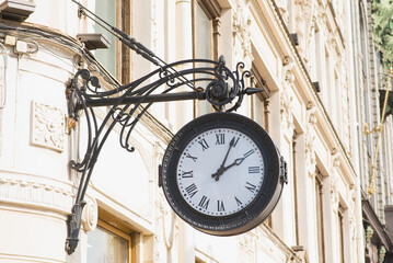 Fototapeta na wymiar Circle aged mechanical metal clock hanging on the wall.