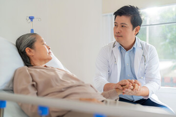 Fototapeta premium Professional Asia doctor holding elderly woman hand who lying down on the bed at nursing home. Caregiver provide care medical service help support smiling old grandma at home care medical