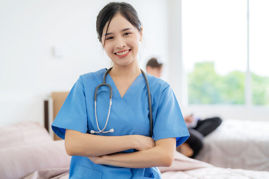 Young Asia Pretty Doctor Standing At Nursing Home With Smile And Cross Armed. Put A Stethoscope Around Neck. Medical Health Care Worker In Blue Uniform Work At Clinic Or Hospital. Business Healthcare