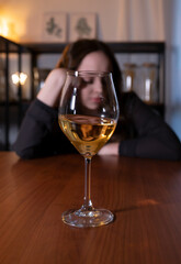 Young woman sitting in the kitchen with a glass of wine. Teen alcoholism concept, alcohol addiction problems among women