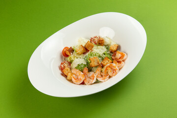Salad with shrimp in a plate on a green background.