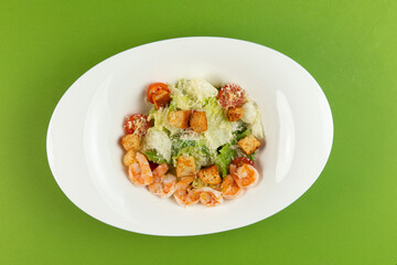 Salad with shrimp in a plate on a green background.