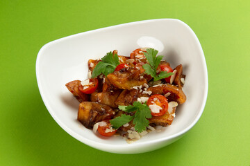 Fried eggplant in a plate on a green background.