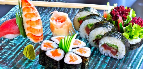 Sushi set with maki and nigiri. Sushi with salmon, tuna, raw fish, on a blue, glass plate.