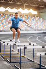 Sports man jumping over barriers at the stadium