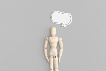 Wooden man with speech bubble on a gray background