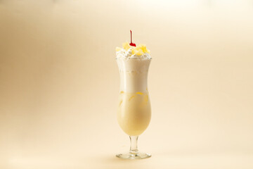 glass of pina colada cocktail on brown background.