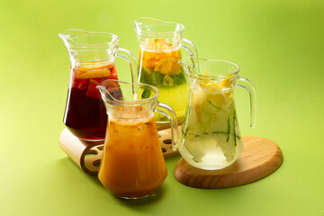 Cocktails and lemonades in decanters on a green background.