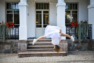 Girl athlete in a white dress makes a jump in the air