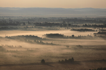 Thick morning fog over the fields at dawn in autumn. Misty landscape in early morning in steppe. Top view