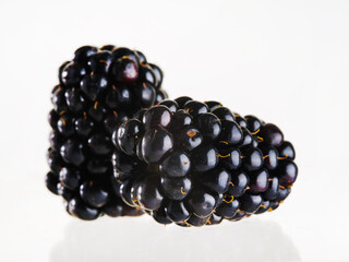 Two ripe dark purple blackberries on a white background. Close-up. Vitamins, minerals, antioxidants. Sweet dessert, cooking. Ingredient for confectionery, sauces.