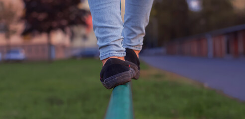 boy walking along the road fence. child keeps balance on the log