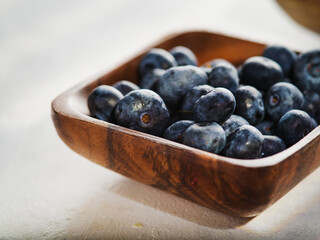 Ripe blueberries in a wooden bowl on a white background. Close-up. Vitamins, antioxidants. Delicious sweet dessert. Healthy food, healthy lifestyle.