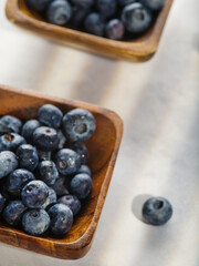 Blueberries in a wooden bowl on a gray background. Low angle view. Farming, cooking, market, supermarket. Environmental protection, ecology, healthy lifestyle.
