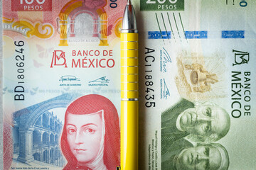 Financial settlements in Mexico, Concept, One hundred and two hundred pesos banknotes, yellow pen...