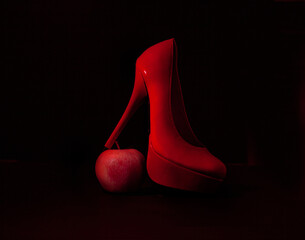 Elegant red shoes an apple on a black background