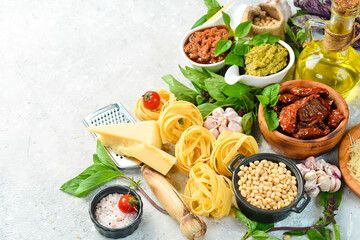 Cooking background: pesto sauce, pasta, basil, parmesan and nuts, olive oil. On a concrete...