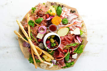 Antipasto Assortment of appetizers: cheese, prosciutto, salami, bacon, olives and capers on a wooden board. Top view. Free space for text.