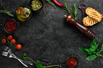 Black kitchen cooking background: vegetables, spices and kitchen utensils. Free space for text.