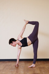 Obraz premium Young pretty yoga girl portrait, doing yoga poses indoors. Beautiful brunette short-haired woman doing pilates exercises. Woman in sports suit meditating. Woman stretching alone, flexible and slim.