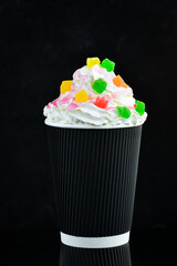 Coffee with candied fruit and cream in a paper cup. on a black background. Free space for text.