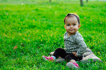 Happy baby sitting on green grass lawn