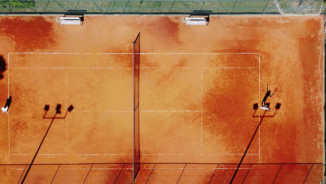 Tennis court drone aerial shot vertical top view, overhead shot of a player shadow silhouette  tennis player on a juicy red coating