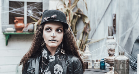 Beautiful scary little girl celebrating halloween. Terrifying black, white half-face makeup,witch...