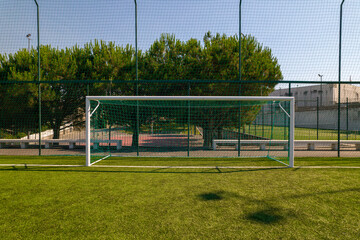 Sports field in a residential area with artificial green grass and football goal at Santo Tirso Municipal Sports Complex in Portugal.