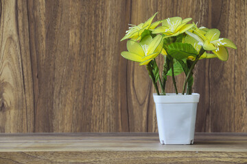 Fake flowers in a vase placed on a table on a wooden table with copy space for design wood grain vintage background