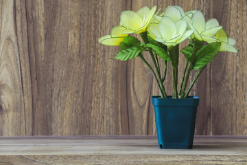 Fake flowers in a vase placed on a table on a wooden table with copy space for design wood grain vintage background.