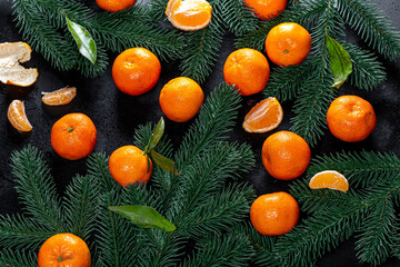 Fototapeta na wymiar Top view fresh tangerines with Christmas tree branches on black background